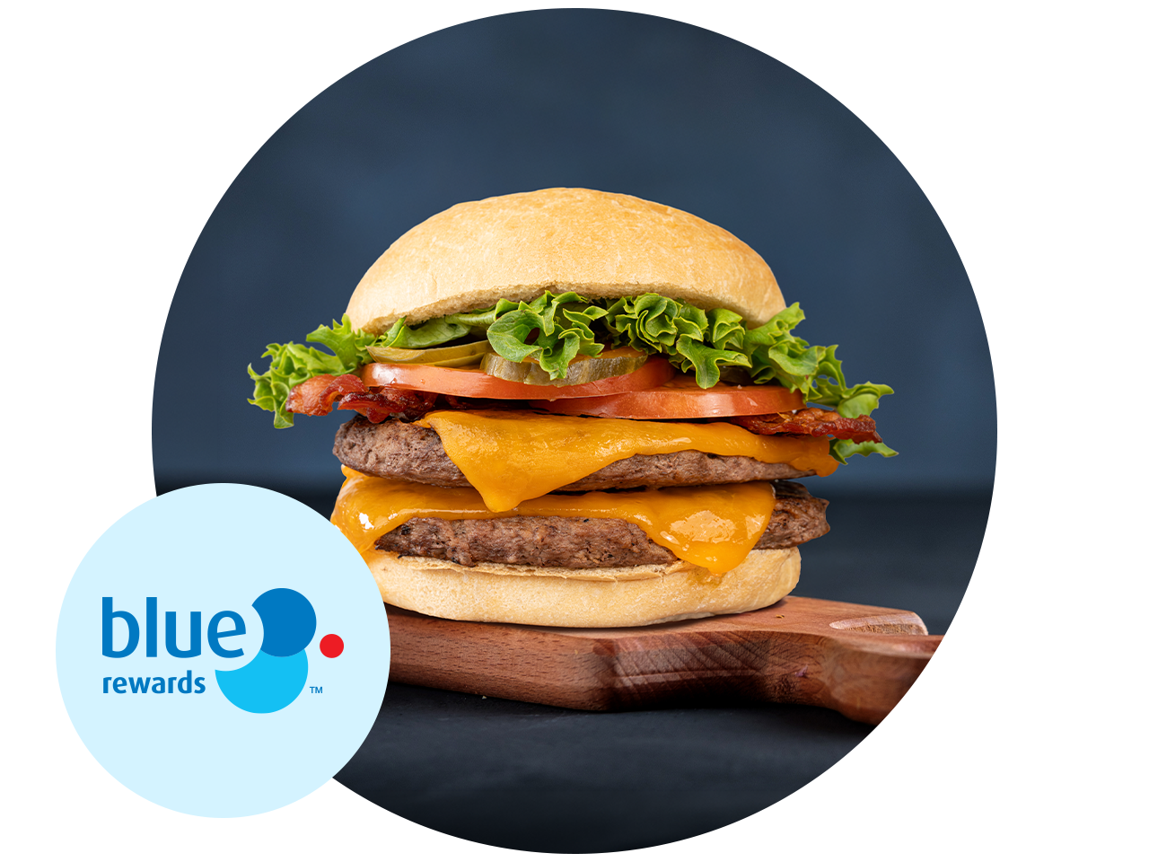 Blue Rewards logo beside a double cheeseburger on a wooden board. The burger is topped with bacon, lettuce, tomato, and pickle slices on a toasted bun.