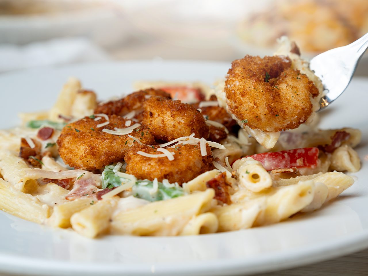 Crispy breaded shrimp served over creamy penne pasta with grated cheese.