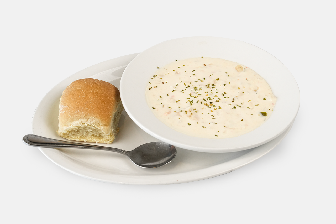 A bowl of Seafood Chowdeer and a roll served on a plate with a spoon