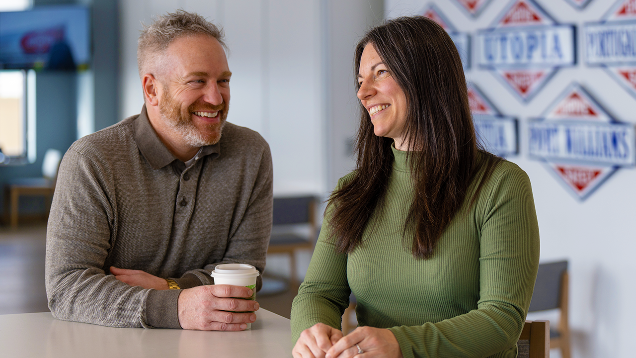 Two people seated at a table having a conversation indoors.