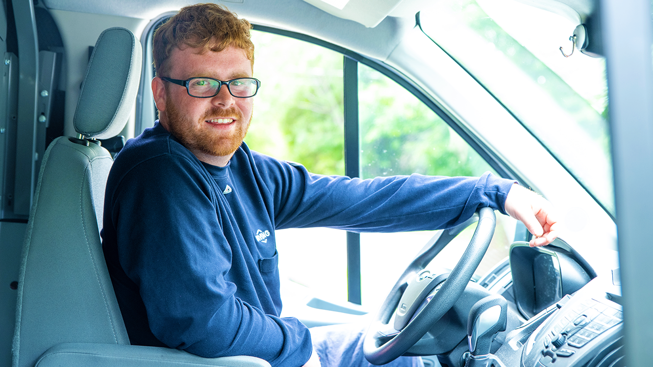 Driver seated behind the wheel of a delivery truck.