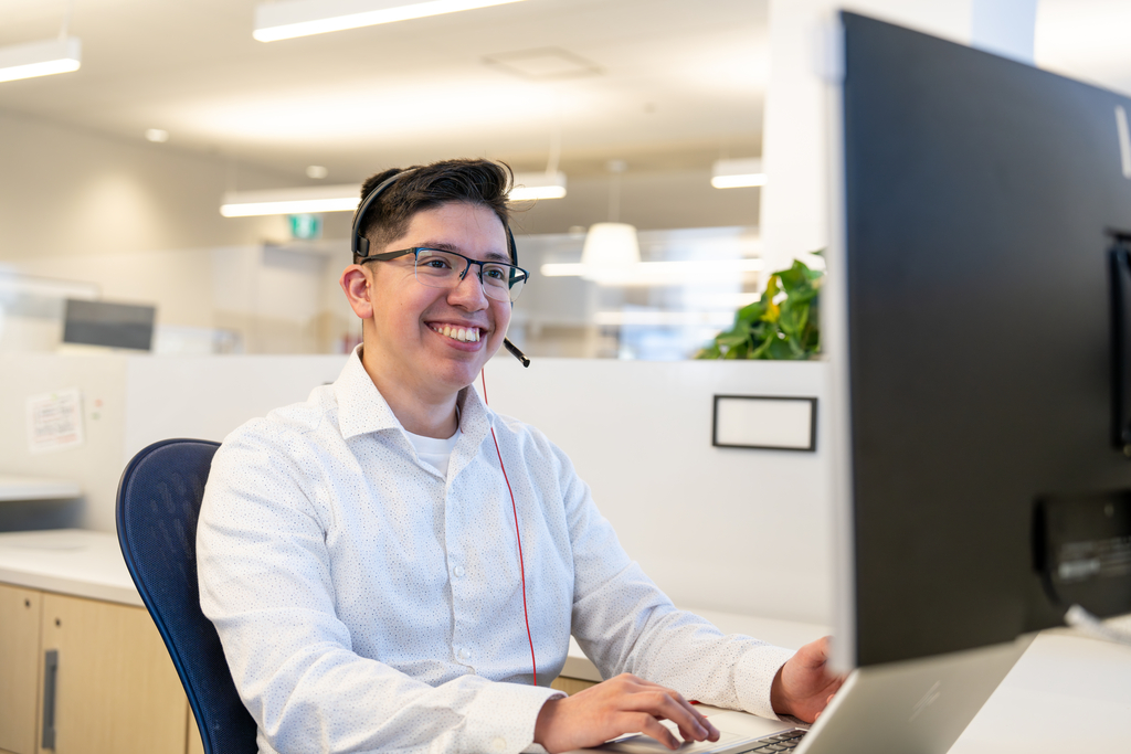 Irving Employee Picture sitting at his desk wearing a white shirt and a headphone over his head
