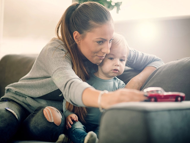 Women and her child happily playing with toy car on the sofa