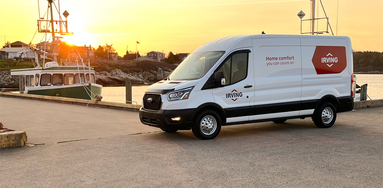 Irving service van parked at a waterfront dock at sunset, with a fishing boat moored nearby and the text “Home comfort you can count on” displayed on the van.